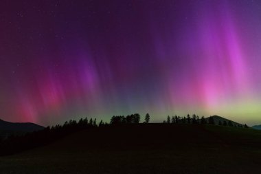 Aurora Borealis, dağların siluetiyle Kuzey Işıkları.