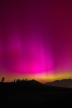 Aurora Borealis, dağların siluetiyle Kuzey Işıkları.