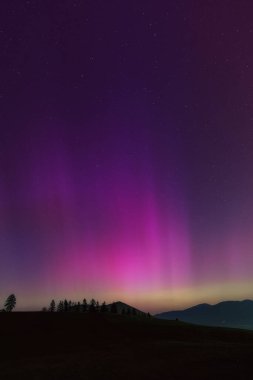 Aurora Borealis, dağların siluetiyle Kuzey Işıkları.