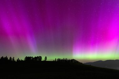 Aurora Borealis, dağların siluetiyle Kuzey Işıkları.