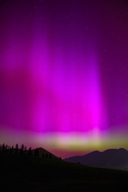 Aurora Borealis, dağların siluetiyle Kuzey Işıkları.