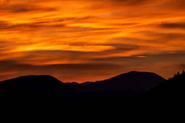 Gökyüzünde renkli turuncu bulutlar sihirli günbatımında tepenin silüetiyle