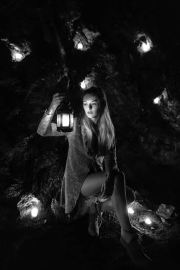 Karanlık tünelde fener ve mumlarla poz veren genç kız..