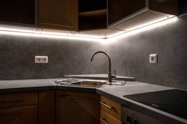 Köşe lavabosu olan mutfak ünitesi ve kurşun ışıklı gri mutfak tezgahı.