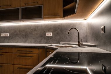 Kahverengi dolapları ve gri mutfak tezgahı olan eski mutfak ünitesi..