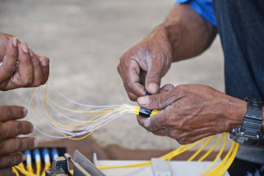 Teknisyen koli bandı kullanıyor. FTTH terminal kutusuna yüklemeden önce fiber optik kablo ile.