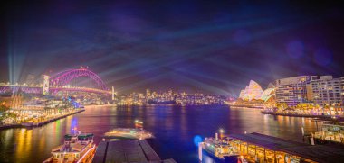 Panorama Vivid Sydney şehri ışıklandırılmış köprüsü, Opera Binası, rıhtım ve aydınlatılmış mimarisi ile geceleyin, Avustralya, 3 Haziran.
