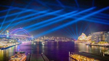 Panorama Vivid Sydney şehri ışıklandırılmış köprüsü, Opera Binası, rıhtım ve aydınlatılmış mimarisi ile geceleyin, Avustralya, 3 Haziran.