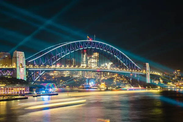 Liman köprüsü ve liman kenti silueti üzerinde renkli Sydney Lazer Gösterisi 3 Haziran 2025 'te Avustralya' da uzun pozlu bir fotoğrafla geceleyin çekildi.