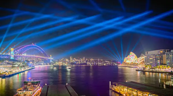Panorama Vivid Sydney şehri ışıklandırılmış köprüsü, Opera Binası, rıhtım ve aydınlatılmış mimarisi ile geceleyin, Avustralya, 3 Haziran.