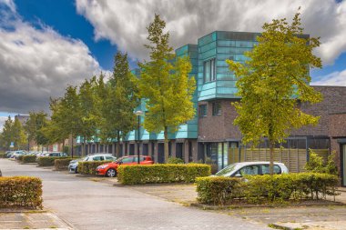 Doğal yeşil caddedeki modern evler. Bahçeleri ve özel park yerleri olan çağdaş bir mahalle. Hollanda, Heerhugowaard 'da sokak manzarası.