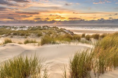 Hollanda, Ameland adasından, Kuzey Denizi 'nde gün batımının üzerindeki kum tepesinden manzara