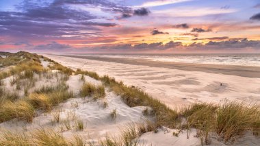 Hollanda, Ameland adasından, Kuzey Denizi 'nde gün batımının üzerindeki kum tepesinden manzara