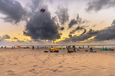 Gün batımında kumullardan görünen uçurtma. Hollanda 'nın Wijk aan Zee sahilinde uçurtma sörfü yapan insanlar..