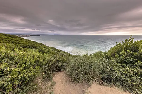 Erretegia Körfezi 'nde gün batımı. Fransız Bask sahilindeki Cor de la Falaise de Bidart plajı. Doğal bitki örtüsünde merdivenlerle yürüme pisti. Biarritz, Biscay Körfezi, Fransa. Avrupa 'da Doğa Manzarası.