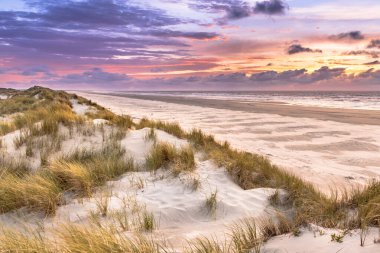 Hollanda 'nın Ameland adasından Kuzey Denizi üzerindeki kum tepesinden gün batımı görüntüsü
