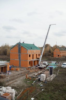 Turuncu tuğla ve betondan yapılmış üç katlı bir evin yapım süreci. Bir inşaat alanının penceresinden görüntüle.