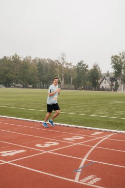 Stadyumda koşucu. Bir adam koşu yarışmasına katılıyor. Genç adam stadyumda koşuyor..