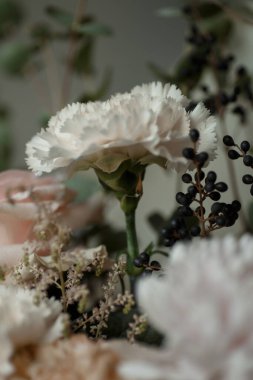 Siyah böğürtlenli beyaz karanfil ve yumuşak pastel çiçekler. Doğal ışık altında zarif bir çiçek buketi, arka plan veya tasarım için mükemmel..