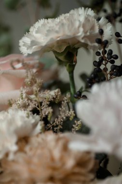 Siyah böğürtlenli beyaz karanfil ve yumuşak pastel çiçekler. Doğal ışık altında zarif bir çiçek buketi, arka plan veya tasarım için mükemmel..