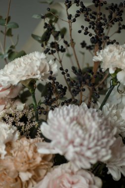 Siyah böğürtlenli beyaz karanfil ve yumuşak pastel çiçekler. Doğal ışık altında zarif bir çiçek buketi, arka plan veya tasarım için mükemmel..