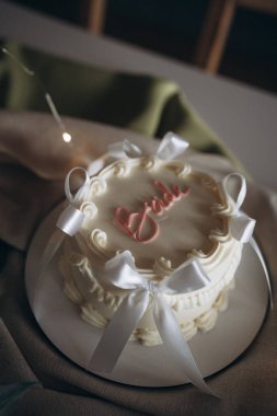 Bekarlığa veda partisi için beyaz kurdeleler, krema ve pembe yazıtlarla süslenmiş güzel bir bento pastası. Piliç partisi için bir pastanın fotoğrafını çek..