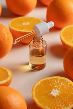 Bir damlacıktaki C vitamini serumunun yakın çekimi, taze, canlı portakal dilimleriyle çevrili. Güzellik ürünü markalaşma modeli
