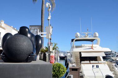 Marbella, Spain - December 10, 2023: Black sculpture of woman next to luxury vessel at Banus Harbor, in Marbella, Spain. clipart