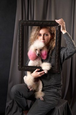 Grinin üstündeki fotoğraf stüdyosunda köpeği olan mutlu bir kız. Beyaz Kaniş ve kıvırcık kadın