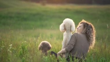İki köpekli kıvırcık saçlı kız gün batımına karşı. Doğadaki kadın ve kanişler güneşte