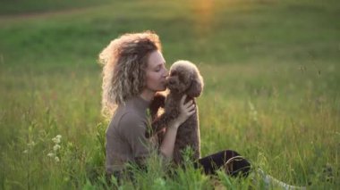 Kıvırcık saçlı, köpekli kız gün batımına karşı. Kadın ve kaniş güneşin altında doğada