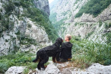 Bir kadın ve Gordon Setter heybetli uçurumlarda huzurlu bir anın tadını çıkarıyorlar. Bu görüntü, kadın ve köpeği arasında barışçıl bir bağ olduğunu gösteriyor.