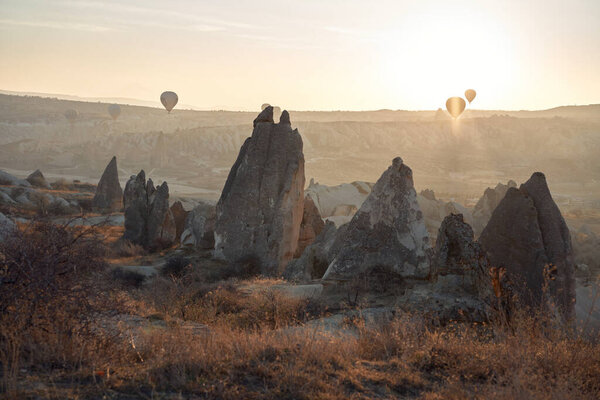 Hot air balloons dot the early morning sky, a serene landscape awakening. The tranquil flight over a rugged terrain provides a picturesque adventure