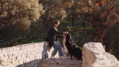 Bernese Dağ Köpeği 'yle parktaki köprüden geçen bir kadın, huzurlu ortamın tadını çıkarıyor..