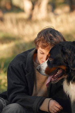 Bir kadın ve Bernese Dağ Köpeği ormanda birlikte vakit geçiriyorlar..