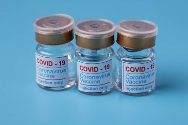 COVID-19 koronavirüs aşısı yakın plan. Enjeksiyon çözeltisi ve şırıngayla dolu cam şişe. Boşluğu kopyala