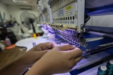 Kota Kinabalu, Sabah, Malezya - 24 Ağustos. 2021: Bir kadın işçi, Kumaş Üretiminde tekstil endüstrisinde nakış makinesi işletiyor