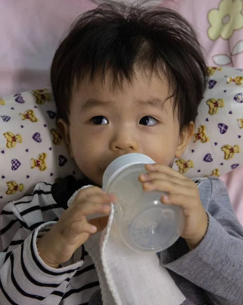 Ασιατικό Κινεζάκι Ξαπλωμένο Στο Κρεβάτι Κρατώντας Ένα Μπουκάλι Γάλα Πίνοντας — Φωτογραφία Αρχείου