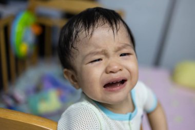 Portrait image of 1 to 2 years old childhood child with face of sad and cry Asian boy in head shot.