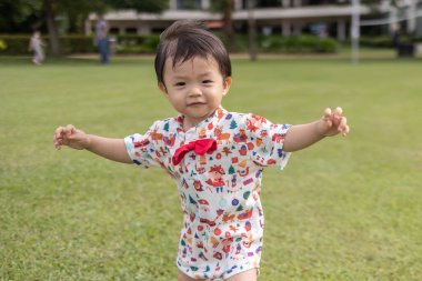 Portrait image of Happy 1-2 years old Asian Chinese child enjoying playing on clean green park