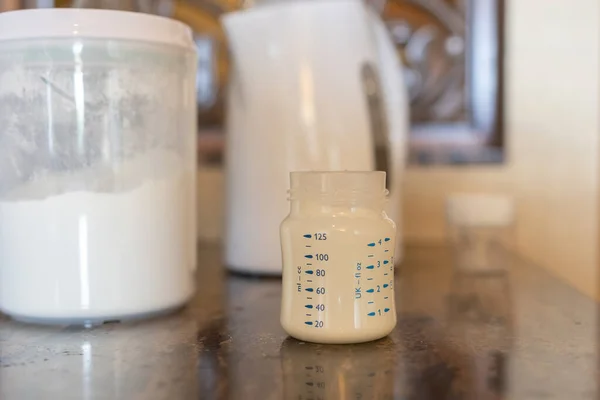 Preparing baby bottle of powdered milk on table