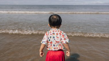 Mutlu küçük çocuk sahilde eğleniyor ve koşuyor.