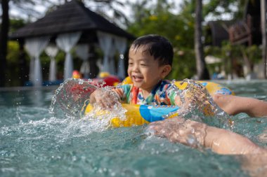 Asyalı bir çocuk mutlu ve çocukların şişme yüzme yüzüğüyle bilardo oynamaktan zevk alıyor.