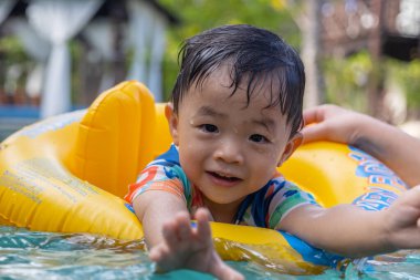 Asyalı bir çocuğun portresi mutlu ve çocukların şişme yüzme yüzüğüyle bilardo oynamaktan zevk alıyor.