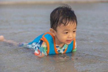 Sahilde oynayan mutlu Asyalı Çinli çocuk. Çocuk dışarıda eğleniyor. Yaz tatili ve sağlıklı yaşam tarzı konsepti