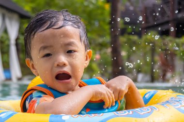 Asyalı bir çocuğun portresi mutlu ve çocukların şişme yüzme yüzüğüyle bilardo oynamaktan zevk alıyor.