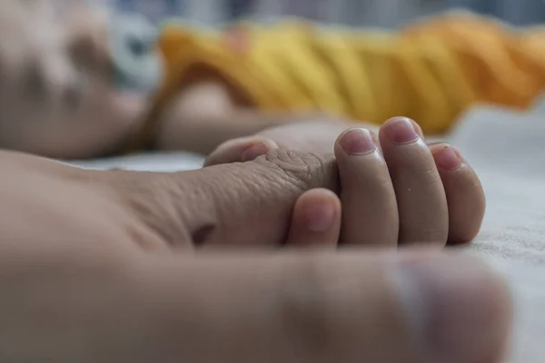A toddler holding father hand during baby sleeping. Father taking care of her son kid happy family dream of health