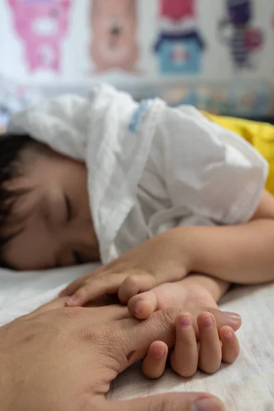 A toddler holding father hand during baby sleeping. Father taking care of her son kid happy family dream of health