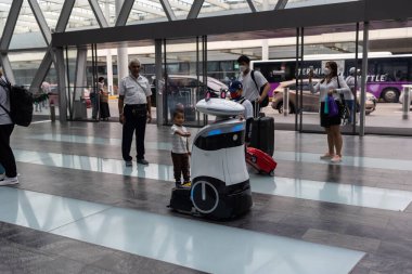SINGAPORE - Kasım 09.2022: Jewel Changi Havaalanı 'nın zeminini temizlemek ve dezenfekte etmek için kullanılan özerk robotla iletişim kurmaya çalışan çocuklar