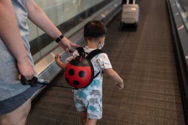 two years old kid traveler walking heading to arrival hall at Changi Airport, Singapore clipart